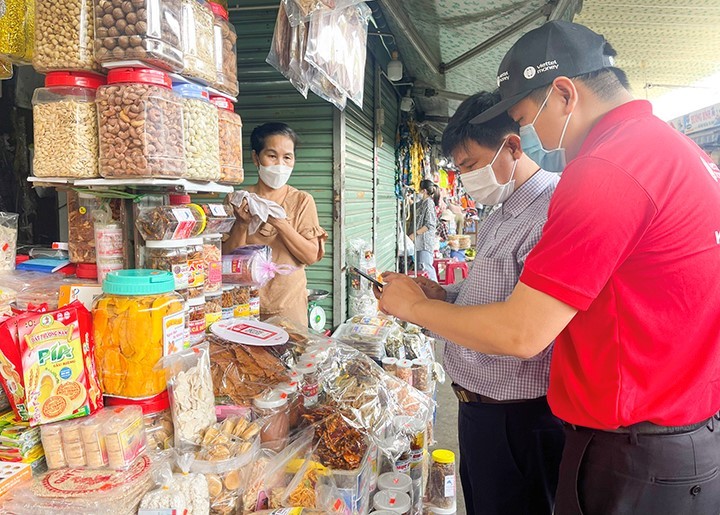 Người dân quét mã QR để giao dịch khi mua sắm tại chợ truyền thống