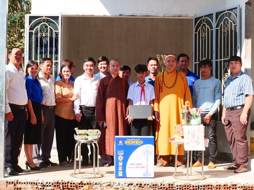 Các đơn vị tài trợ cùng chính quyền địa phương chụp hình lưu niệm cùng gia đình em Nguyễn Huỳnh Quốc Bảo tại lễ bàn giao Nhà Khăn quàng đỏ.